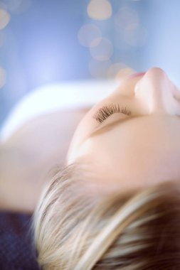 Masaj masasında uzanmış gözleri kapalı rahatlayan genç bir kadın. - Kadın. Spa salonu