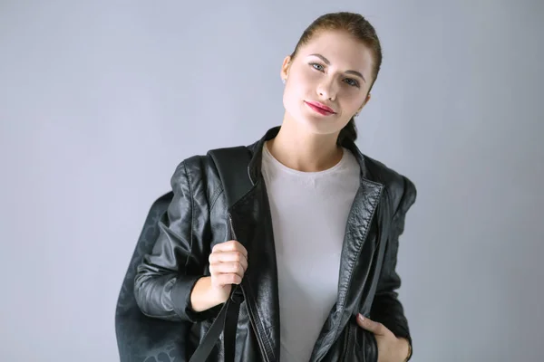 Портрет красивой юной брюнетки в стильной черной куртке на сером — стоковое фото