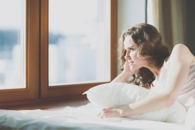 Pencere yakınındaki erken sabah yatakta yatan kadın.