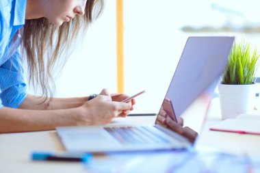 Ofis masasında oturan ve cep telefonuyla konuşan genç ve güzel bir iş kadını. İş kadını