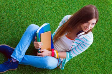 Yeşil çimlerde oturan dizüstü bilgisayarı olan genç bir kadın. Portreit genç bayan