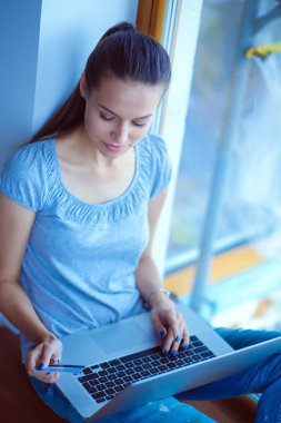 Evde bir dizüstü bilgisayar kullanan genç güzel kadın. Genç güzel kadın.