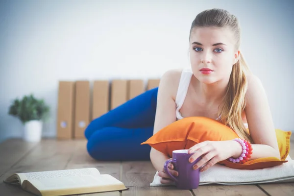 Lachende jonge vrouw liggend op een witte vloer met kussen. — Stockfoto