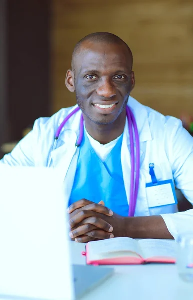 若いアフリカ人の医者は机の上のノートパソコンで働いている。先生。職場 — ストック写真
