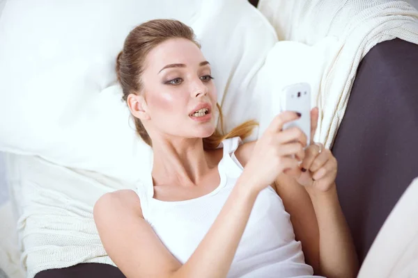 Pretty woman in her living room sitting on the couch sending messages — Stock Photo, Image