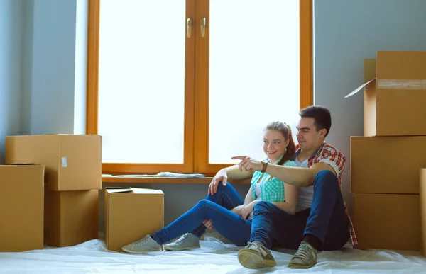 Couple moving in house sitting on the floor. Couple