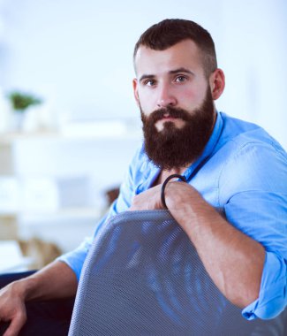 Yakışıklı genç adam dizüstü bilgisayarda oturuyor ve çalışıyor.