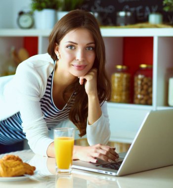 Genç bayan mutfakta masanın yanında oturuyor.