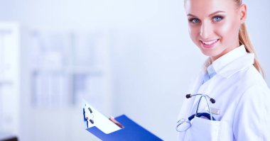 Güzel, genç, gülümseyen bayan doktor masada oturuyor ve yazıyor..