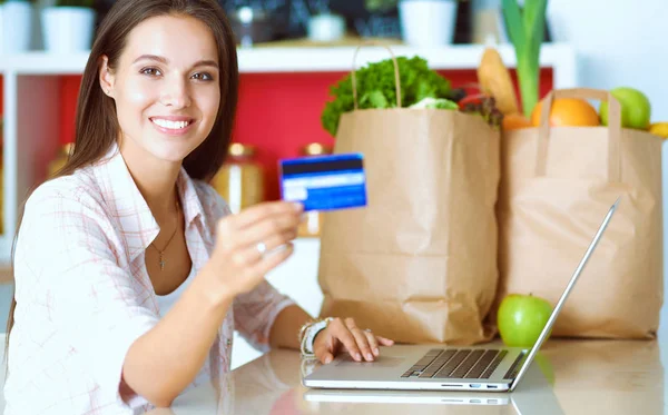 Smiling woman online shopping using tablet and credit card in kitchen — Stock Photo, Image