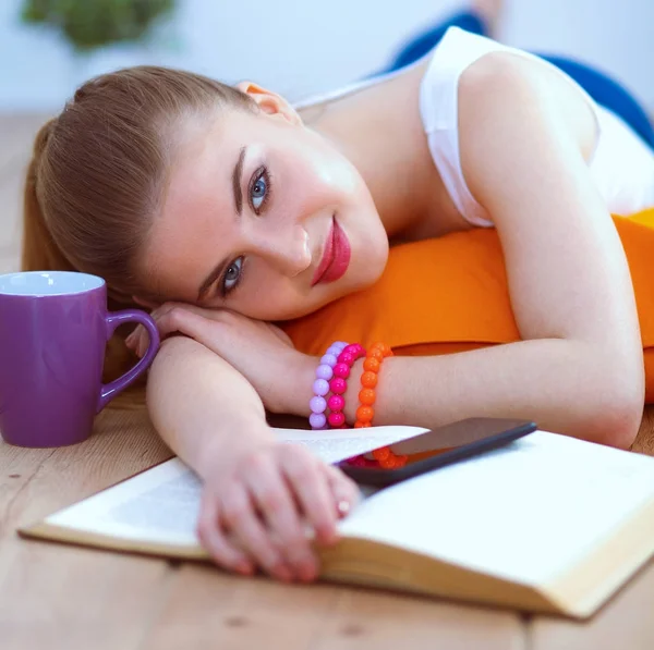 Lachende jonge vrouw liggend op een witte vloer met kussen — Stockfoto