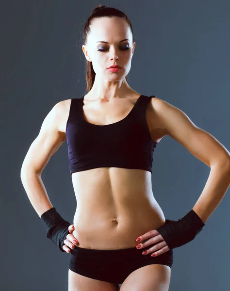 Muskulöse junge Frau steht auf grauem Hintergrund — Stockfoto