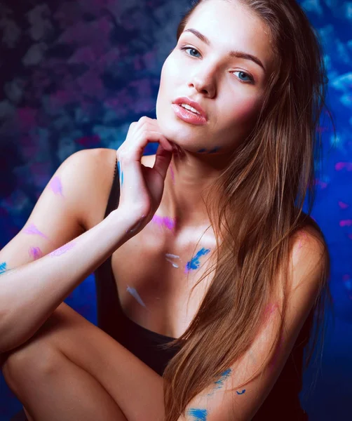 Mujer hermosa joven sentada cerca de la pared de pintura — Foto de Stock