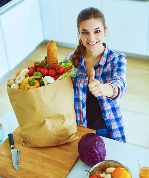 Fiatal nő gazdaság élelmiszerbolt bevásárló táska zöldségekkel, és mutatja, oké — Stock Fotó