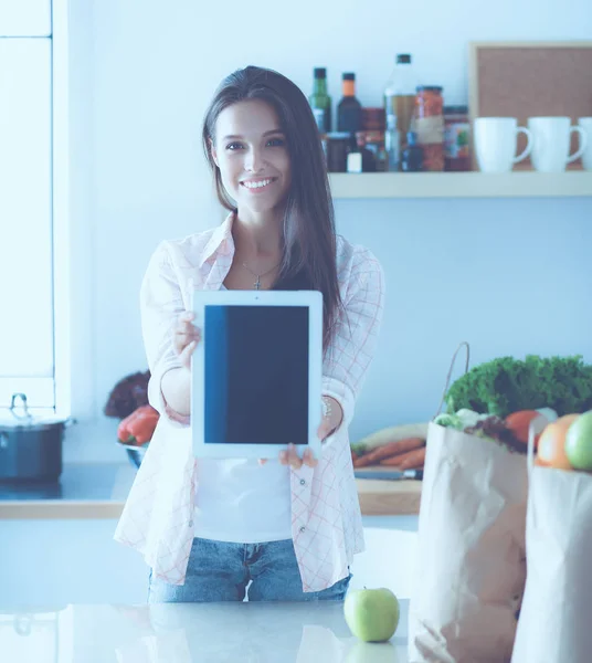 Mutfakta yemek yapmak için tablet bilgisayar kullanan genç bir kadın. — Stok fotoğraf