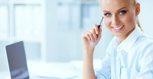 Attractive businesswoman sitting on a desk with laptop in the office — Stock Photo, Image