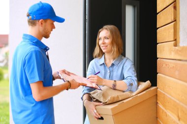 Mavi üniformalı gülümseyen kurye servis konseptine paket kutusu teslim eden teslimatçı. Mavi üniformalı gülümseyen teslimatçı.