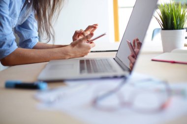 Ofis masasında oturan ve cep telefonuyla konuşan genç ve güzel bir iş kadını. İş kadını