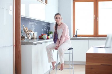 Mutfakta masada oturan genç kadın.