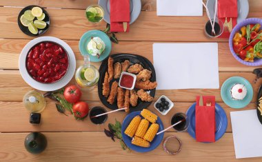 Ahşap masada otururken birlikte yemek yiyen bir grup insanın üst düzey görüntüsü. Masada yemek var. İnsanlar fast food yiyor..