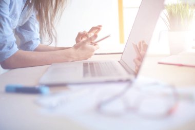 Ofis masasında oturan ve cep telefonuyla konuşan genç ve güzel bir iş kadını. İş kadını