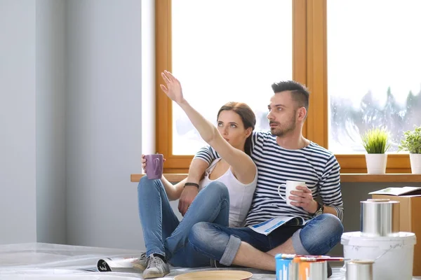 Yeni evin içini boyayan mutlu, gülümseyen genç bir çift portresi. Genç çift