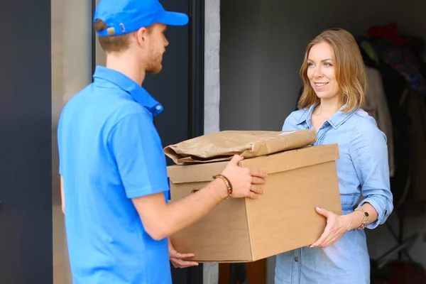 Pengantar senyum dengan seragam biru mengantarkan kotak paket ke penerima konsep layanan kurir. Pria pengiriman senyum dengan seragam biru — Stok Foto