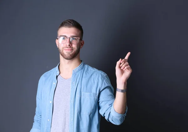 Portret van een glimlachende jonge man die omhoog wijst. — Stockfoto