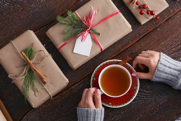 Noel hediye kutusu ile masaya oturan kadın. Kadının elleri