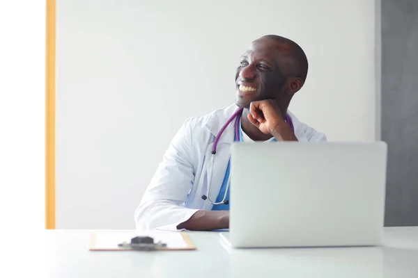 Porträt eines jungen männlichen Arztes, der ein Headset trägt, während er Computer am Schreibtisch in der Klinik benutzt. Arzt. — Stockfoto