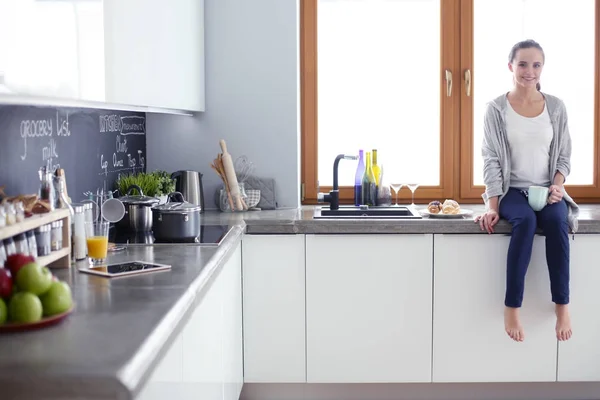 Hermosa joven usando una tableta digital en la cocina. — Foto de Stock