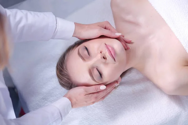 Mujer joven acostada en una mesa de masaje, relajándose con los ojos cerrados. Una mujer. Salón de spa —  Fotos de Stock