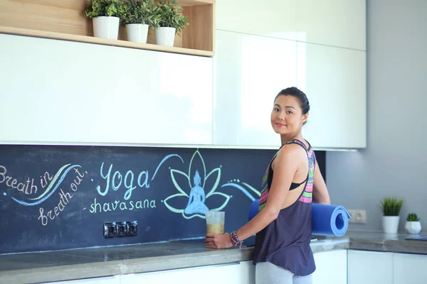 Retrato de una mujer sonriente sosteniendo en su mano una esterilla de yoga mientras estaba de pie en el estudio. Yoga. Una mujer. Bienestar — Foto de Stock