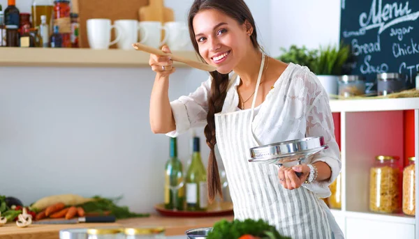 Mutfakta sobanın yanında duran genç bir kadın.