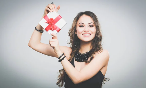 年轻女人幸福的微笑举行礼品盒在手中，在灰色的背景中分离 — 图库照片