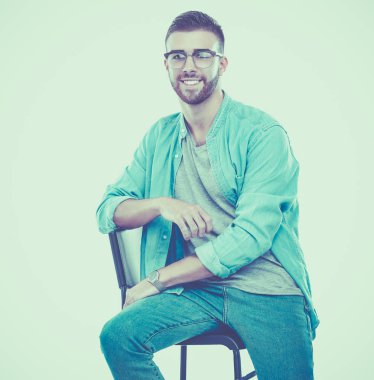 Beyaz arka plan üzerinde izole sandalye üzerinde oturan genç adam