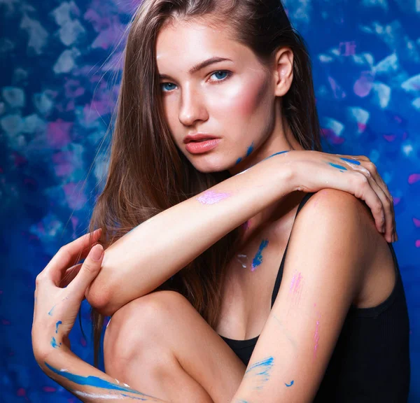 Young beautiful woman sitting near painting wall — Stock Photo, Image