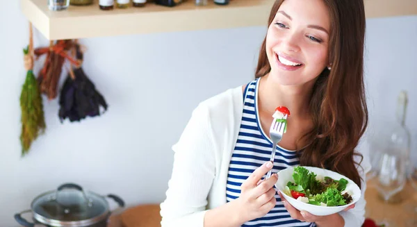 Young woman eating salad and holding a mixed salad