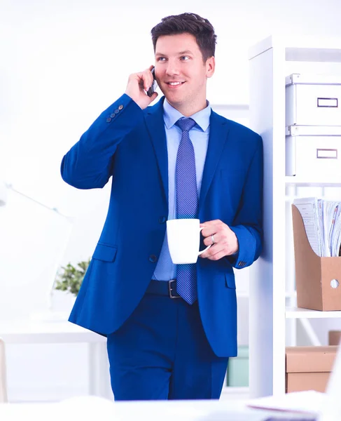 Lachende zakenman permanent en mobiele telefoon gebruiken in office — Stockfoto