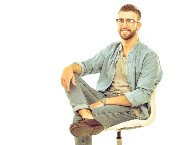 Junger Mann sitzt isoliert auf dem Stuhl vor weißem Hintergrund — Stockfoto