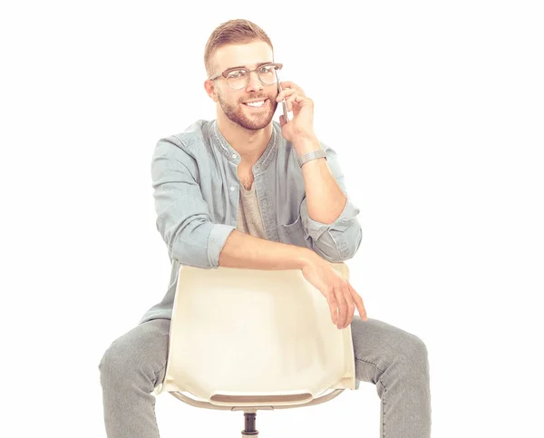 Junger Mann sitzt auf Stuhl und benutzt Handy — Stockfoto