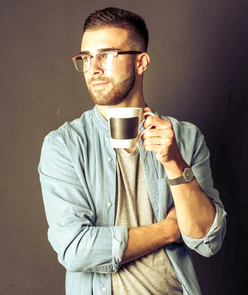 英俊的年轻男子站在捧着一杯咖啡在他手中的画像 — 图库照片