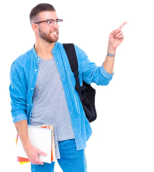 Um estudante do sexo masculino com um saco escolar segurando livros e apontando isolado em fundo branco — Fotografia de Stock