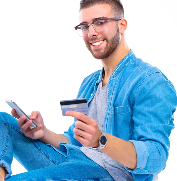 Joven sentado en la silla y con tarjeta de crédito — Foto de Stock