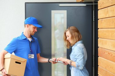 Mavi üniformalı gülümseyen kurye servis konseptine paket kutusu teslim eden teslimatçı. Mavi üniformalı gülümseyen teslimatçı.