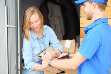 Mavi üniformalı gülümseyen kurye servis konseptine paket kutusu teslim eden teslimatçı. Mavi üniformalı gülümseyen teslimatçı.