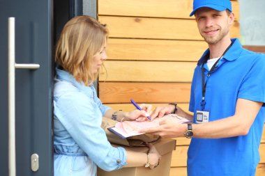 Mavi üniformalı gülümseyen kurye servis konseptine paket kutusu teslim eden teslimatçı. Mavi üniformalı gülümseyen teslimatçı.