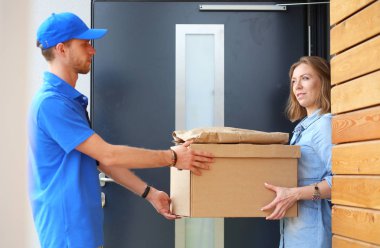 Mavi üniformalı gülümseyen kurye servis konseptine paket kutusu teslim eden teslimatçı. Mavi üniformalı gülümseyen teslimatçı.