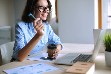 Ofis masasında oturan genç bir kadın dizüstü bilgisayar ekranına bakıyor. Genç kadın.