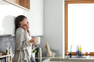 modern mutfakta otururken cep telefonu kullanan kadın.